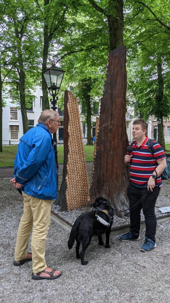 Ferry en Louis staan bij het beeld Triomf waarin de houtenblokjes afsteken tegen de boomstructuur aan de buitenzijde.