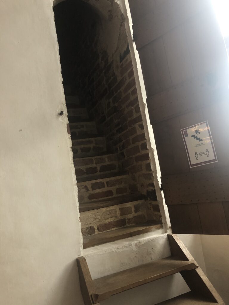 Achter een smalle houten deur ligt een stijlen stenen trap verborgen